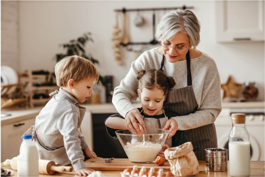 A grandparent helping their grandchildren bake in the kitchen